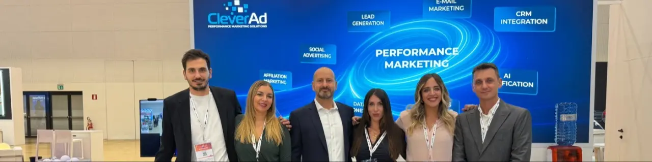 Il team CleverAd allo stand di una fiera di settore, davanti al pannello con le aree di attività.